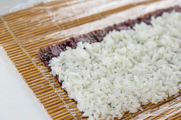 Close up of sushi chef hands preparing japanese food. Man cooking sushi at restaurant. Traditional asian seafood rolls on cutting board.