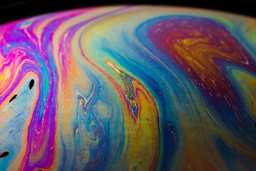 The colorful close-up surface of a soap bubble with weird psychedelic background and...