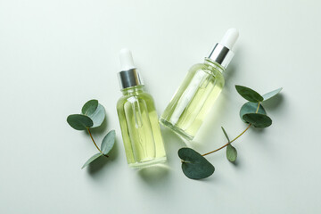 Dropper bottles of eucalyptus oil and twigs on white background