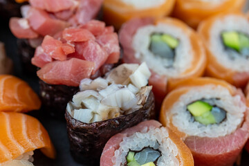 Sushi rolls prepared by professional asian chef with traditional Japanese ingredients. Salmon fish, rice, vegetables, sesame seeds.  Sushi cooking and seafood making concept