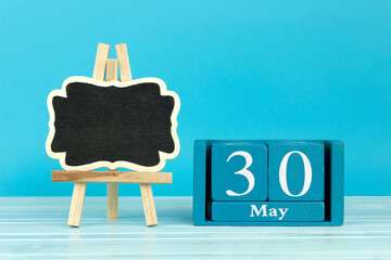 wooden calendar with date 30 May and easel on blue background, place for text, International Cuddle Your Cat Day; World Asthma and Allergy Day; International Multiple Sclerosis Day