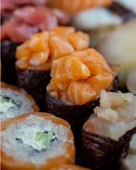 Sushi rolls prepared by professional asian chef with traditional Japanese ingredients. Salmon fish, rice, vegetables, sesame seeds.  Sushi cooking and seafood making concept