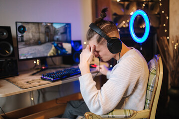 Men playing online video games at home using powerful computer. Streamer man using professional microphone, keypad, mouse in gaming home studio. Man losing the game