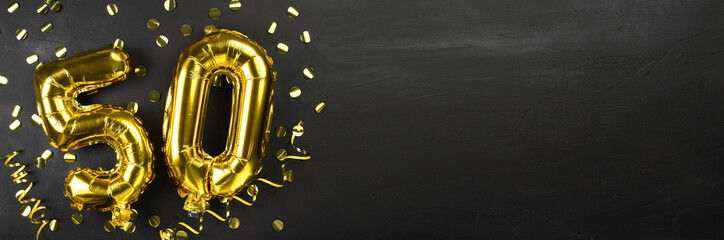 golden foil balloon number fifty. Birthday or anniversary card with the inscription 50. Black concrete background. Anniversary celebration. Banner. - obrazy, fototapety, plakaty