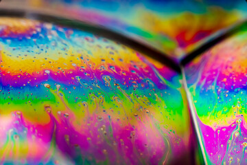 The colorful close-up surface of a soap bubble with weird psychedelic background and...