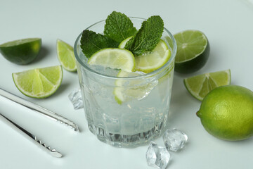 Glass of mojito cocktail and ingredients on white background