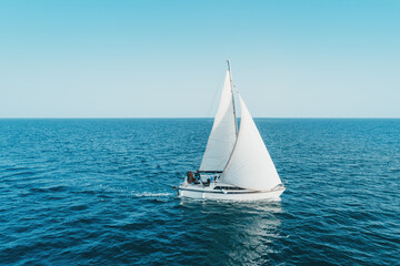 Regatta sailing ship yachts with white sails at opened sea. Aerial view of sailboat in windy...