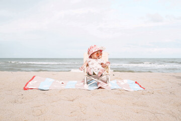 Asian baby girl sitting on beach chair and wearing sunglasses.