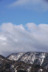 雲の浮かぶ青空と残雪の山脈。