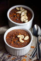 Chocolate vegan dessert - aquafaba mousse - egg free, non-dairy cocoa souffle with lavender, flower petal and cashew nuts on dark moody background, closeup, vegan and vegetarian food concept