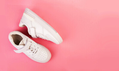 pair of white leather sneakers isolated on pink background