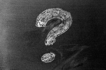 White color chalk hand drawing in question mark shape on blackboard or chalkboard background with...