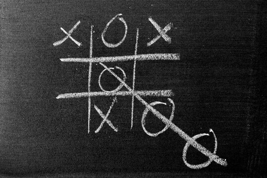 White color chalk hand drawing as Tic Tac Toe with the winner and loser shape on blackboard or chalkboard background