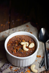 Chocolate vegan dessert - aquafaba mousse - egg free, non-dairy cocoa souffle with lavender, flower petal and cashew nuts on dark moody background, closeup, vegan and vegetarian food concept