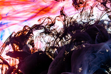 Cloud of colorful ink in water. Abstract paints swirling in water. Multicolored beautiful oil paints in fantastic motion. Chaotic Movement of blue, red and purple, and black colors.