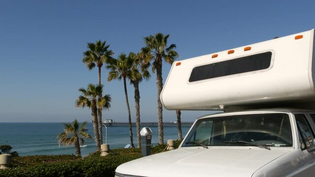 Motorhome trailer or caravan for road trip. Waterfront tropical palm trees and pacific ocean beach, Oceanside California USA. Beachfront vacations in camper van, RV motor home. Mobile home campervan.