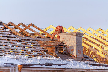 Workers perform repairs to the roof of the house. In winter