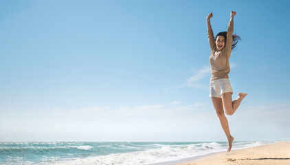 Fototapeta na wymiar Summer relaxation and vacation concept with copy space, Happy carefree asian female smiling jump on beach