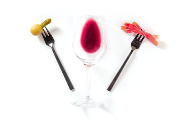 Wine snacks. A glass of wine with an olive and a slice of jamon on forks