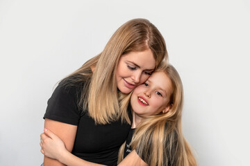 Shot of a happy cheerful mom hugging her little daughter with love against white basckground