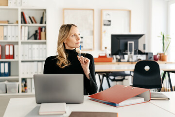 Thoughtful businesswoman looking aside in contemplation as she works in an office