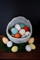 Colorful Easter eggs in wicker basket on black background