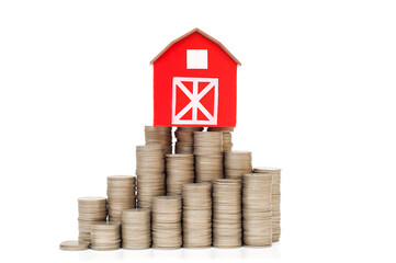 Coins in a stack for saving money and a small red house. Business investment growth concept. 