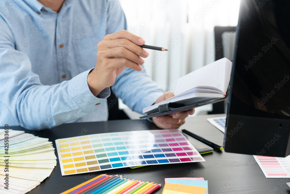 Poster graphic designer or creative working together coloring using graphics tablet and a stylus at desk wi