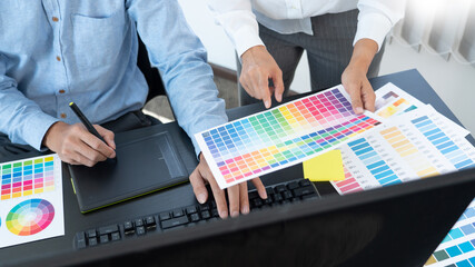 Graphic designer or creative working together coloring using graphics tablet and a stylus at desk...