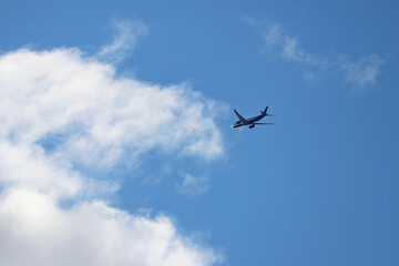 Airplane flying in the blue sky with clouds. Commercial plane at flight, travel concept