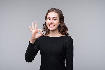 Beautiful young woman wearing black sweater showing thumb up gesture and smiling