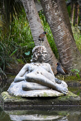 Beautiful birds on woman sculpture on a lake in the park
