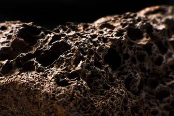 Close up of a black patterned volcanic rock. Background texture of a stone   