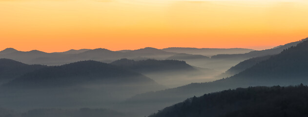 Fototapeta na wymiar foggy, misty valley short before sunrise, beautiful orange yellow lighted sky