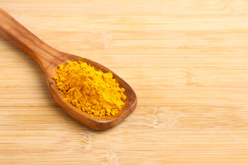 Turmeric in wooden spoon on white background.
