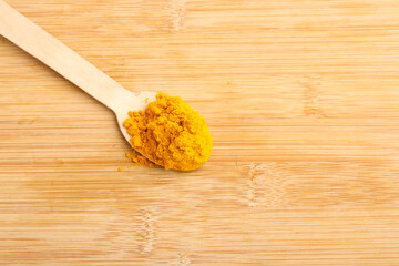 Turmeric in wooden spoon on white background.