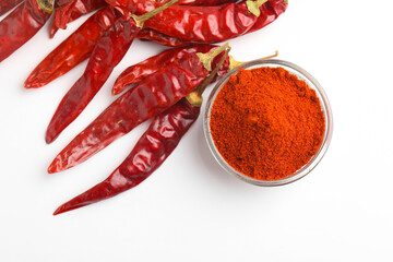 Dried red chilli and powder in glass bowl on white background.