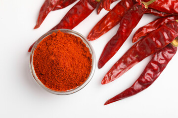 Dried red chilli and powder in glass bowl on white background.