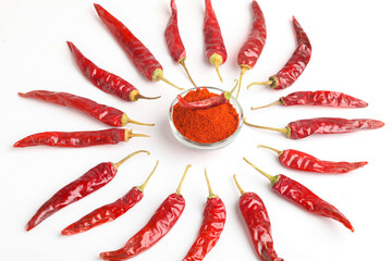Dried red chilli and powder in glass bowl on white background.