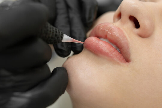 Close-up of the permanent makeup procedure. Lip makeup in the cosmetologist's salon.