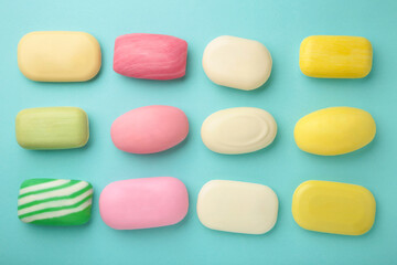Different soaps in different soap dishes. A lot of solid soap for hygiene and cleanliness. Colorful soap and remnants are scattered on mint background.