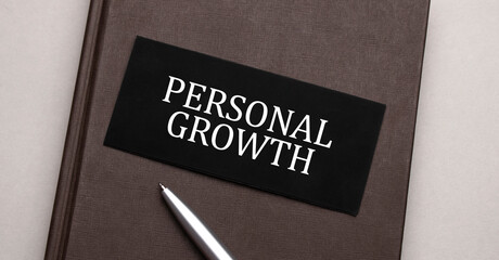 PERSONAL GROWTH sign written on the black sticker on the brown notepad. Tax concept