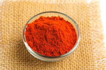 Red chilli powder in glass bowl on white background.