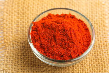 Red chilli powder in glass bowl on white background.