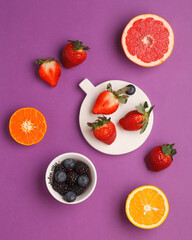Naklejka premium Exotic fruits on bright backgrounds. Pineapple, avocado, citrus fruits, berries on colored backgrounds. Bright and juicy fruits