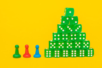 Group of green dice lies in the form of a pyramid or stacks in ascending order on a yellow background with three red, blue and green game chips with space for text, business or casino concept