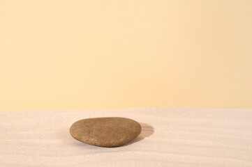 Sandy podium with stone for cosmetic product against beige background.