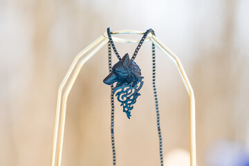 Pendant wolf head necklace black color shoot outside in a sunny day closeup. Selective Focus. High...