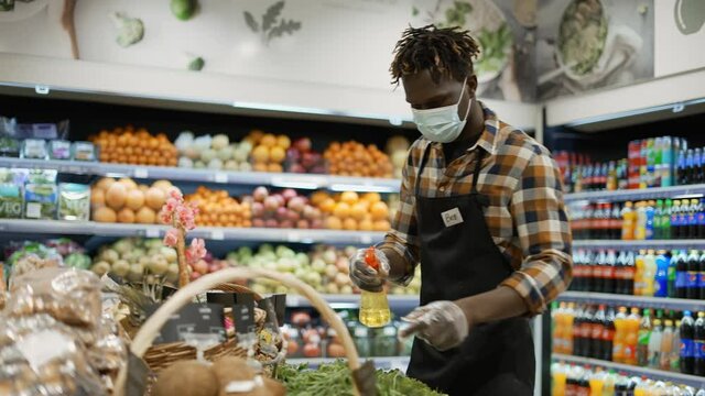 African american worker refreshing and arranging greens in the store