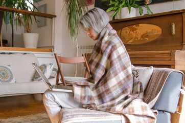 A casually dressed young woman is doing freelance work, on the laptop, from her home decorated in vintage style.
